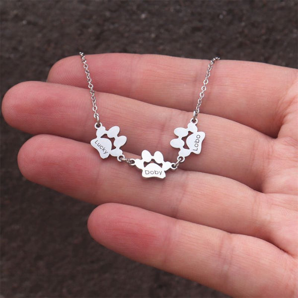 Collier Pattes de Chien Personnalisé avec prénoms Lucky, Doby, Lobo tenu en main