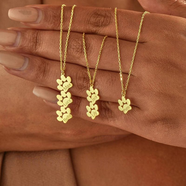Trois modèles de Collier Patte de Chien Personnalisé tenus à la main avec différents prénoms