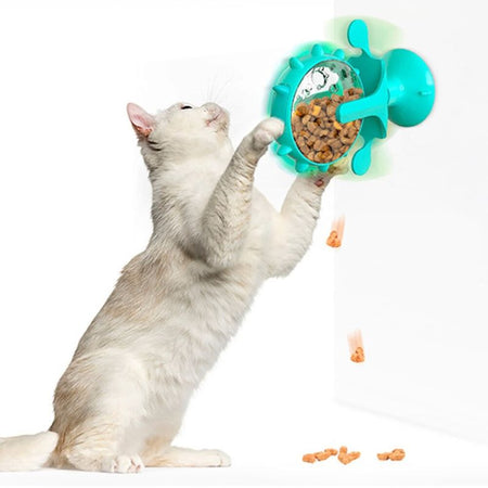 Chat blanc jouant avec un Jouet Distributeur De Croquettes Pour Chat fixé au mur.