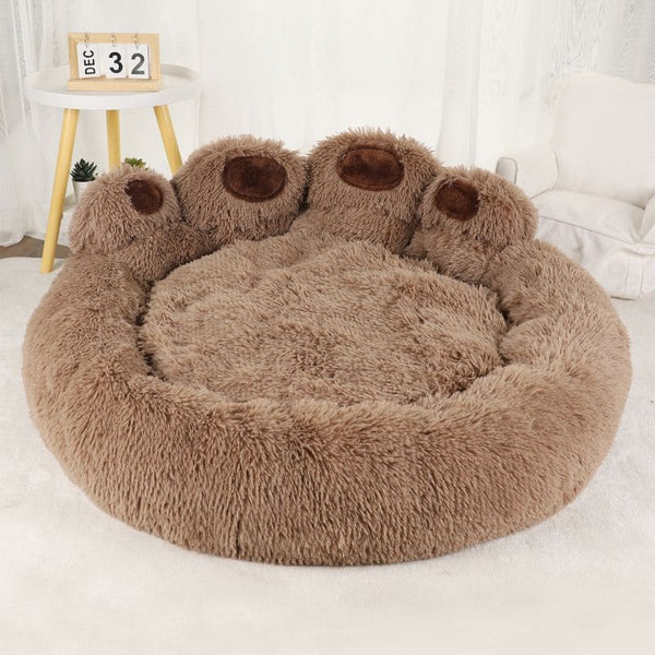 Coussin pour chien en forme de patte marron sans chien, vu de face dans un salon blanc