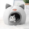 Chat qui observe depuis l'entrée de la Niche Chat Intérieur Igloo Chat sur tapis blanc - Toutou Love