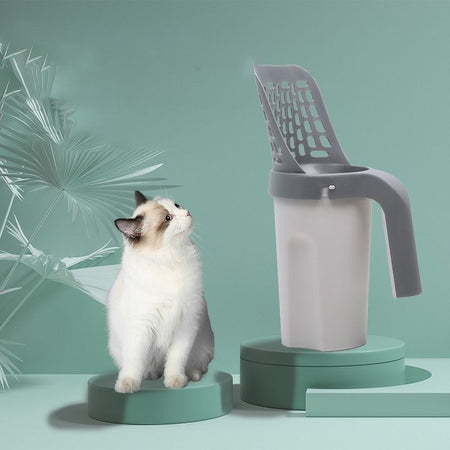 Pelle à Litière pour Chat présentée debout aux côtés d’un chat blanc sur fond vert stylisé - Toutou Love